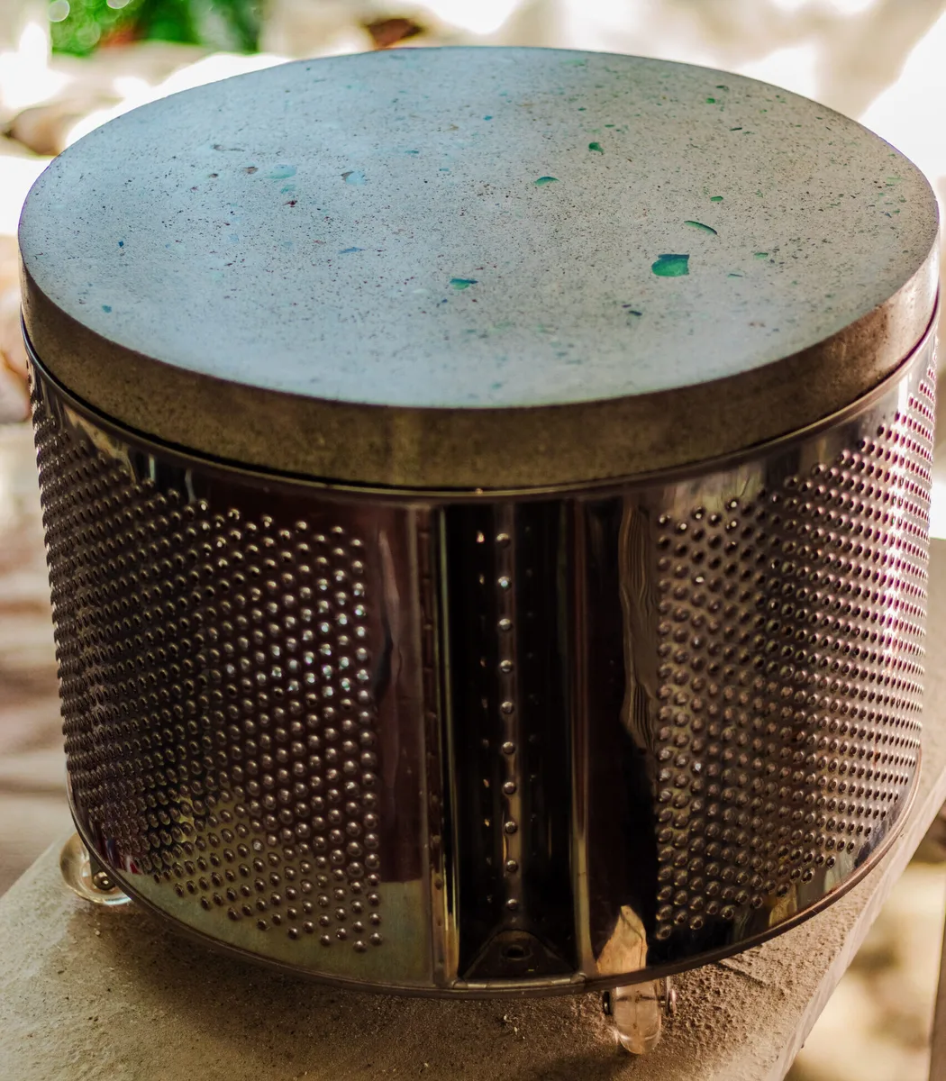 Mesa de apoio redonda feita de tambor metálico de máquina de lavar com tampo de concreto